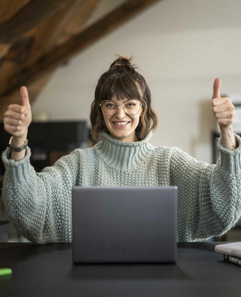wiasano userin zeigt beide daumen in die hoehe hinter ihrem laptop sitzend sie ist zufrieden